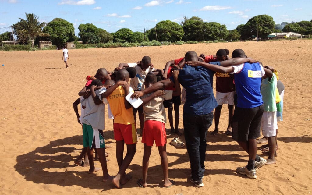 af mozambique - prier avant de jouer au football sur un terrain en terre battue