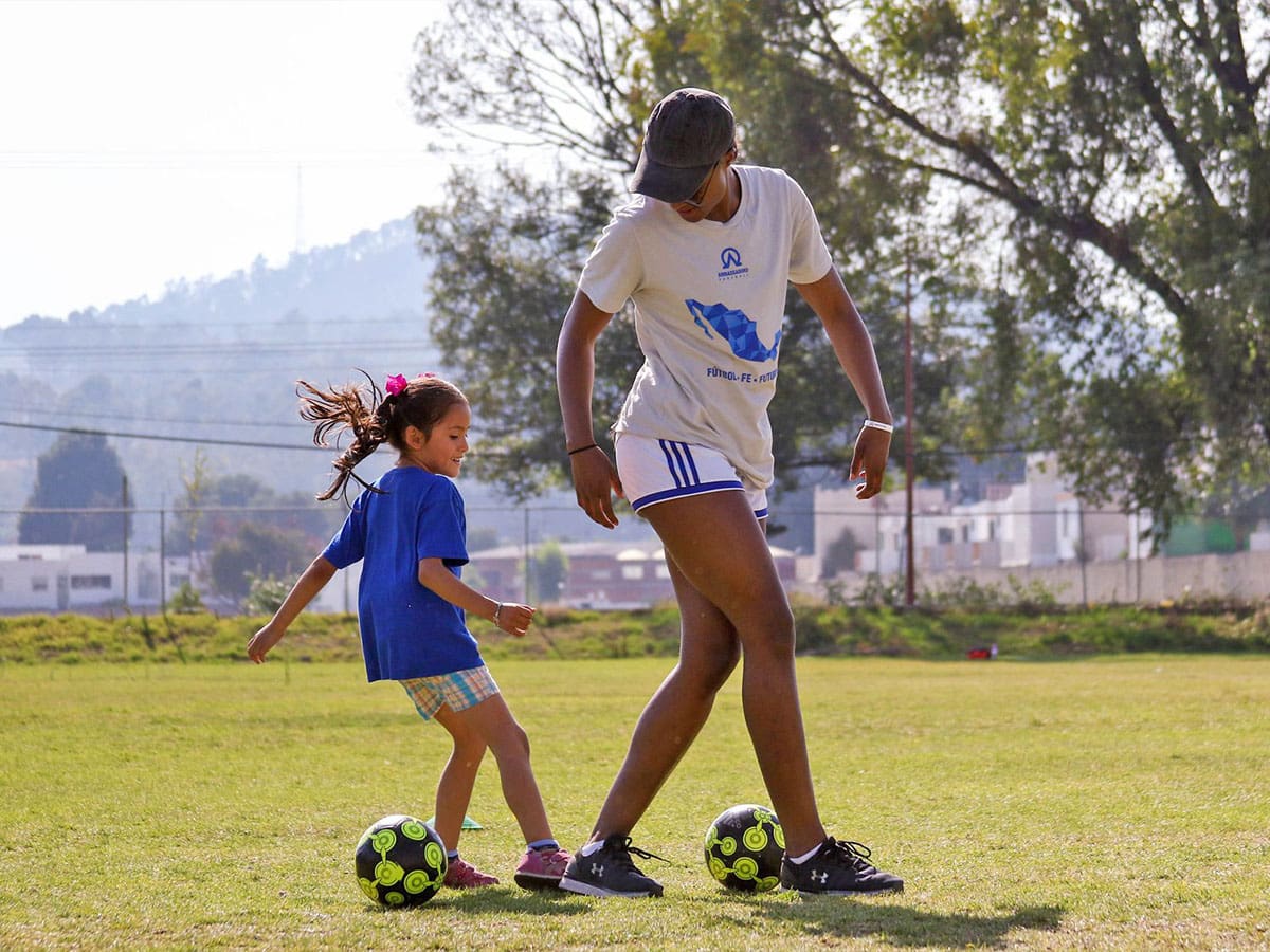 jeune femme jouant au football avec une fille