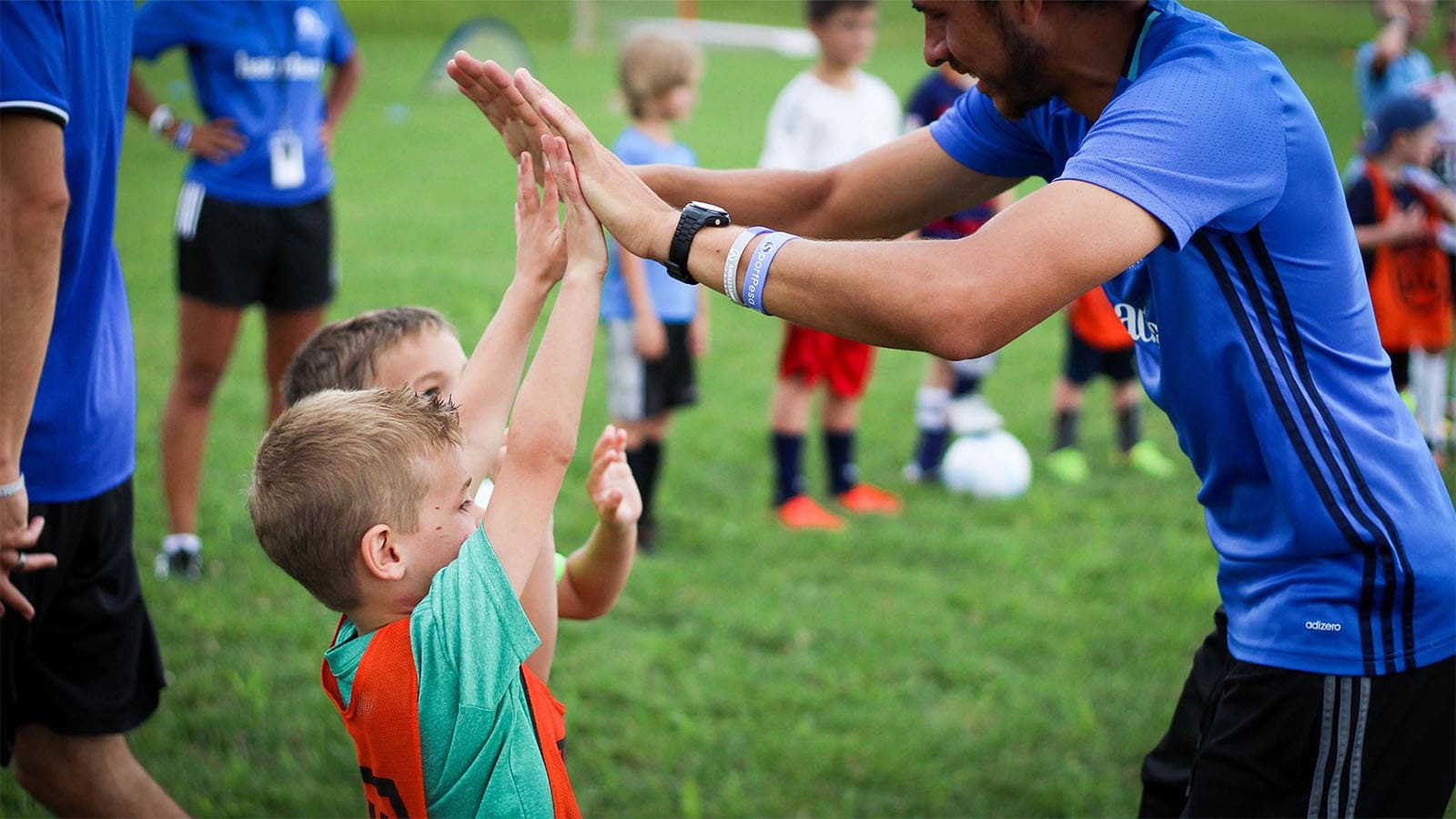 des jeunes enfants font un high five &agrave; leur entra&icirc;neur de football