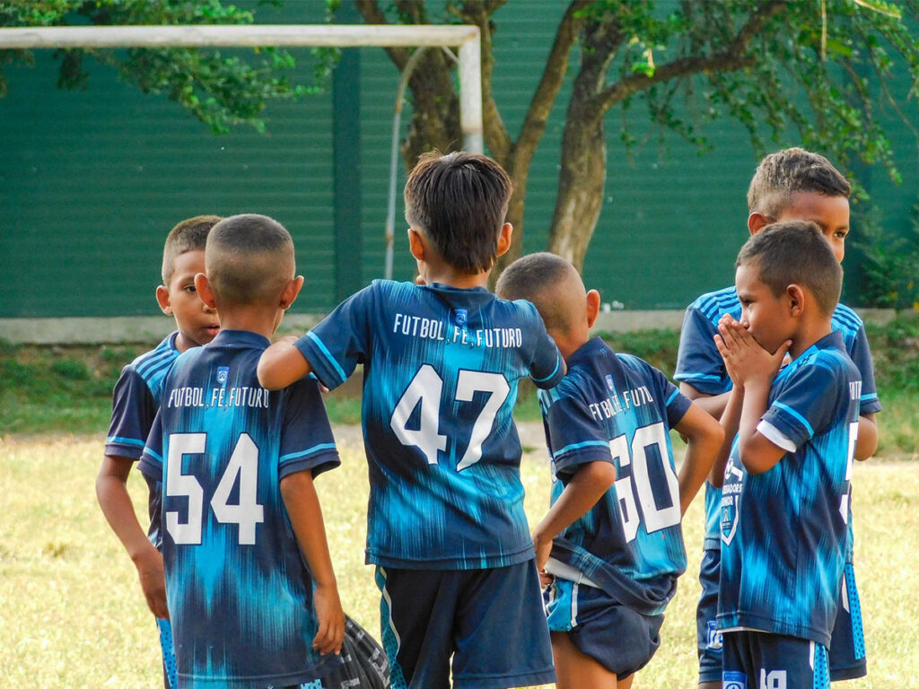 boys huddled together on football field at ambassadors football colombia