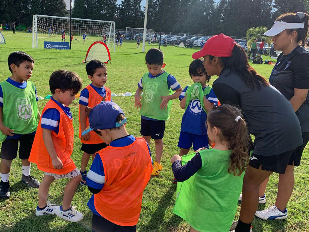 group of kids huddled with coach at Ambassadors Football Mexico