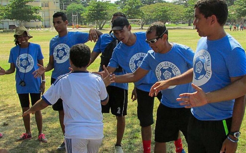 young soccer coaches in colombia high fiving a kid at soccer camp