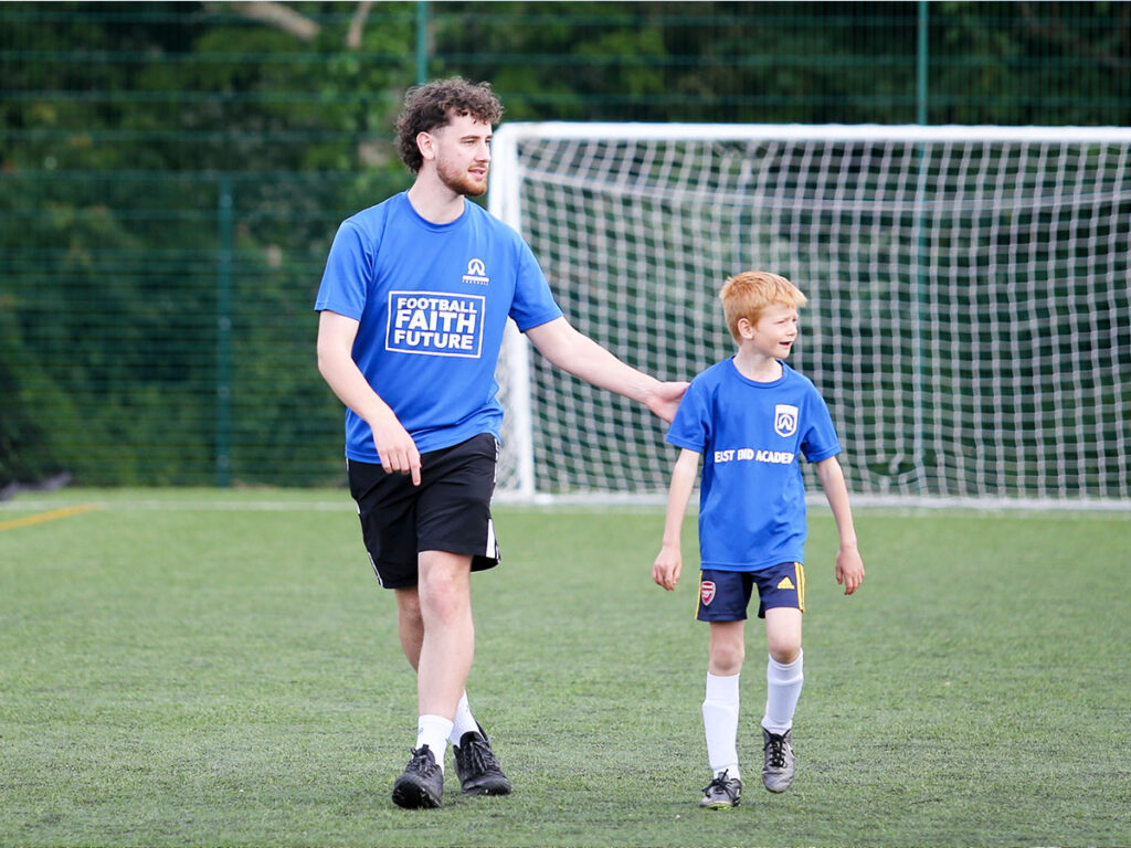 coach walking with a young boy on the football field