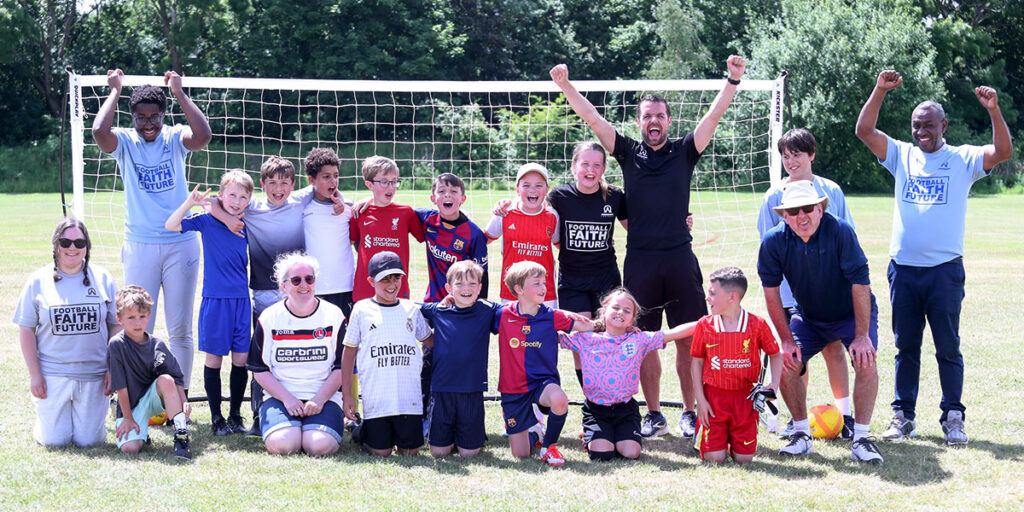 excited leaders and kids raising arms in front of a football goal
