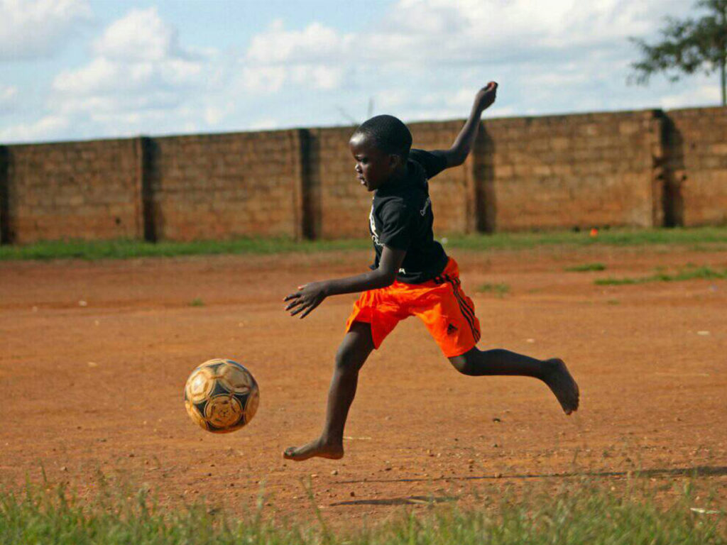 kid kicking football at Ambassadors Football Zambia