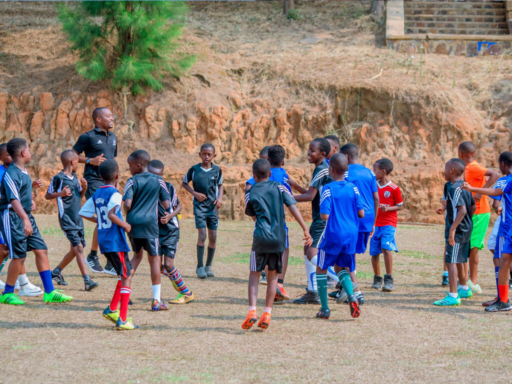 kids and coach playing football during summer football camp in rwanda